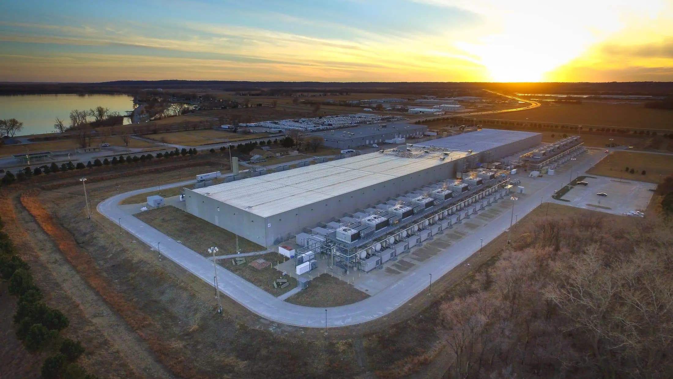 A hyperscale data center building and its generator yard at sunset